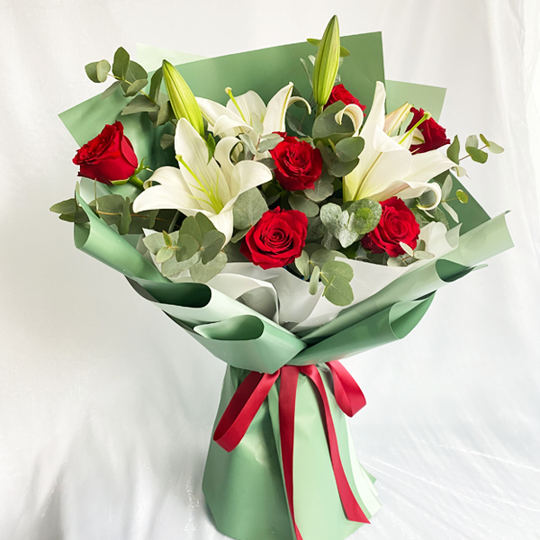 Elegant standing bouquet featuring red roses, white lilies, and eucalyptus greenery by Giflorist